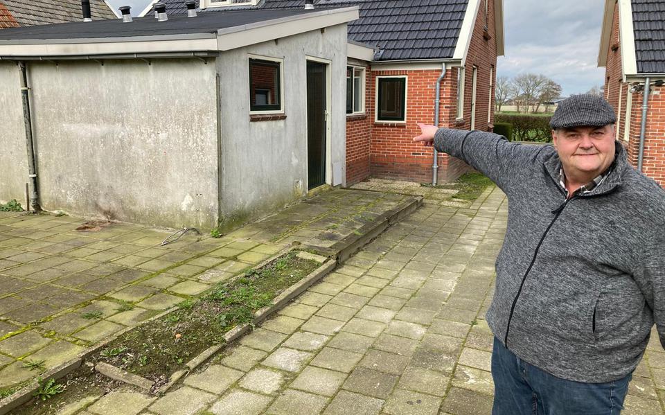 Bewoner Luit van Dijk wijst naar de gerenoveerde huizen naast zijn woning aan de Slagtersrijge in Ezinge.