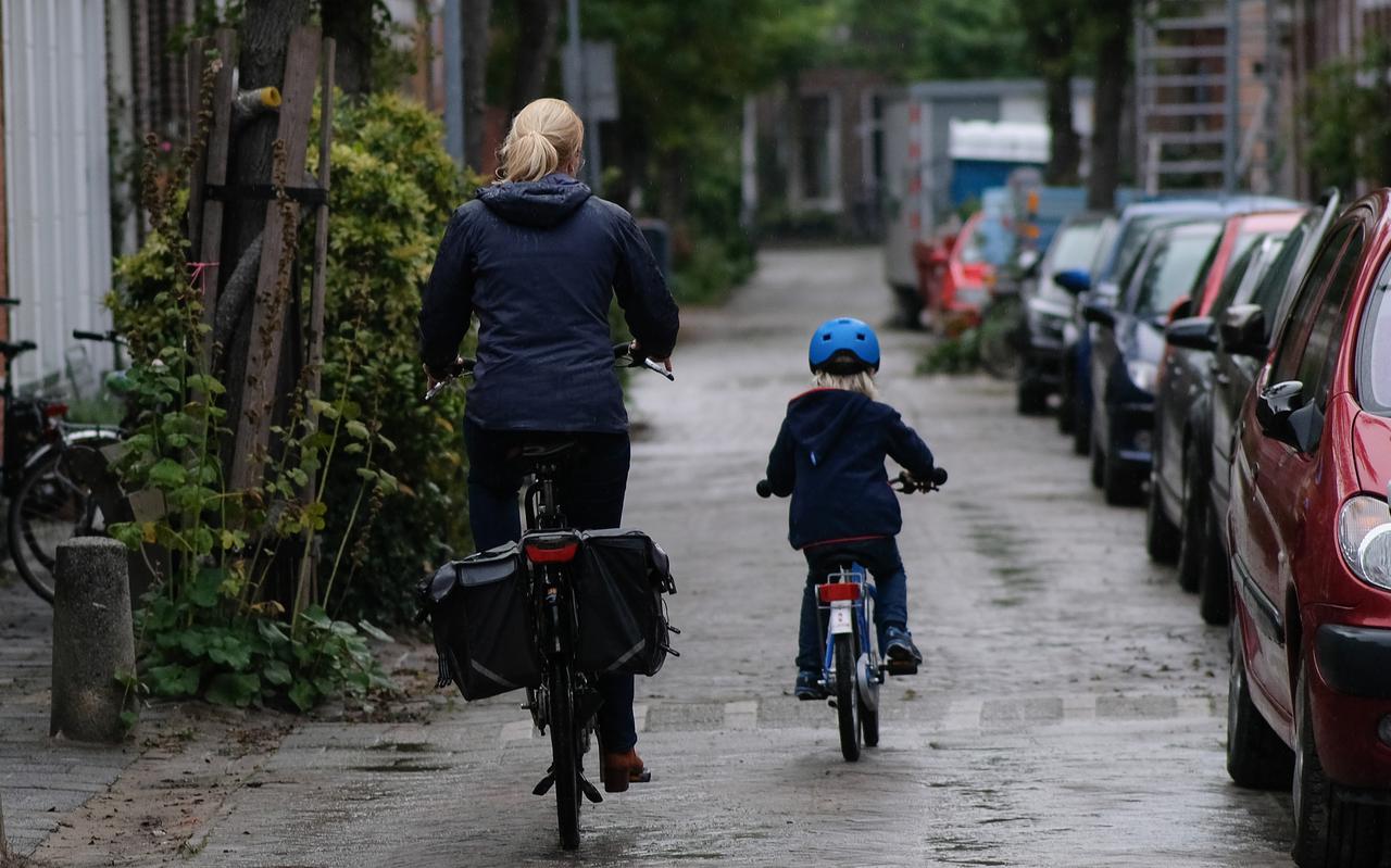 Moeder zonder, dochter met helm op de fiets in Groningen.
