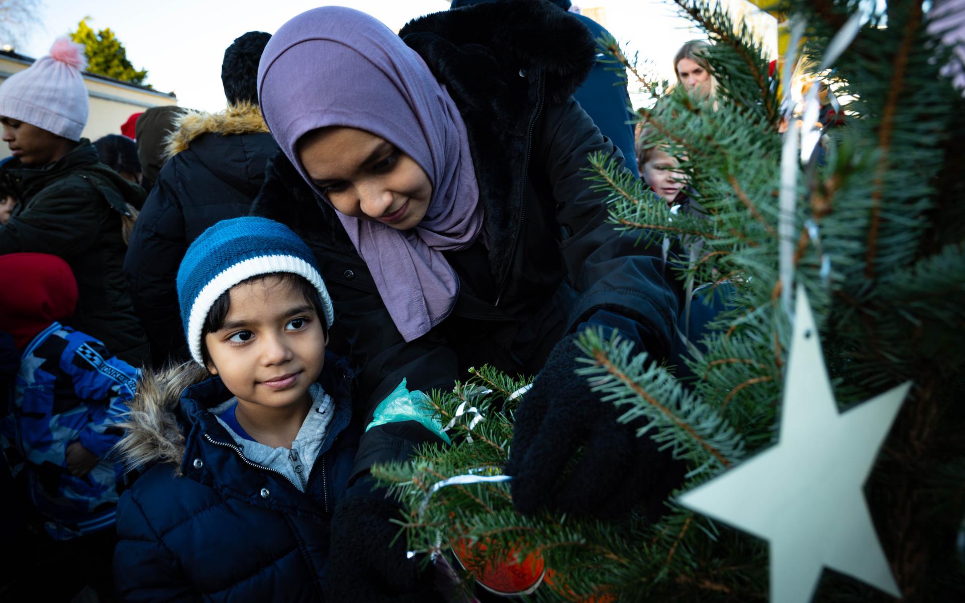 Kinderen uit de noodopvang in Zuidbroek versieren de kerstboom. Door het gebrek aan opvang en doorstroming van statushouders zijn veel asielzoekers aangewezen op noodopvang.