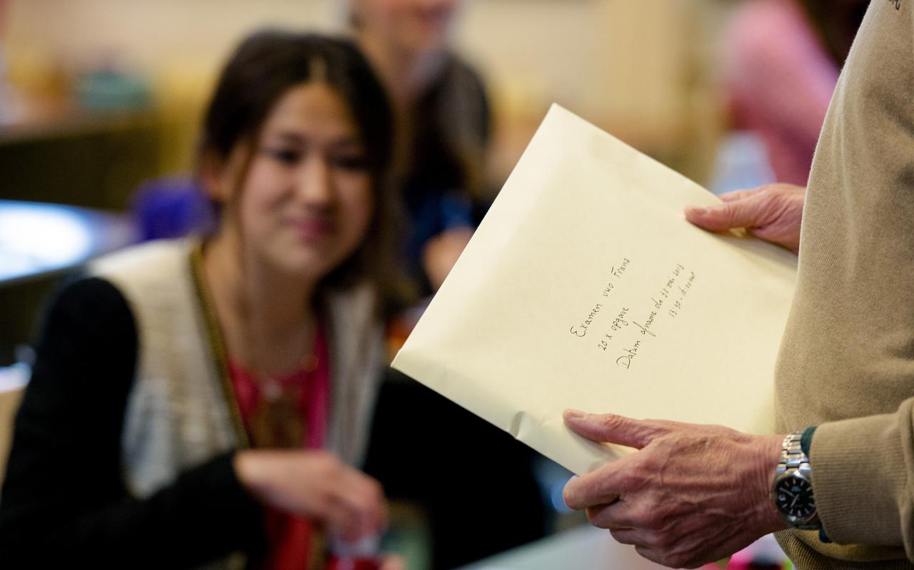 De conrector met de gesloten envelop in zijn hand voor het verlate examen Frans voor het VWO op het Maerlant-Lyceum.