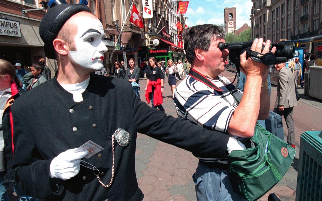 Een mimespeler (in dienst van de politie) rolt de tas van een toerist die rustig bezig is met zijn videocamera. Na zijn daad geeft hij de gerolde voorwerpen weer terug met een waarschuwing erbij. Een mimespeler (in dienst van de politie) rolt de tas van een toerist die rustig bezig is met zijn videocamera. Na zijn daad geeft hij de gerolde voorwerpen weer terug met een waarschuwing erbij.