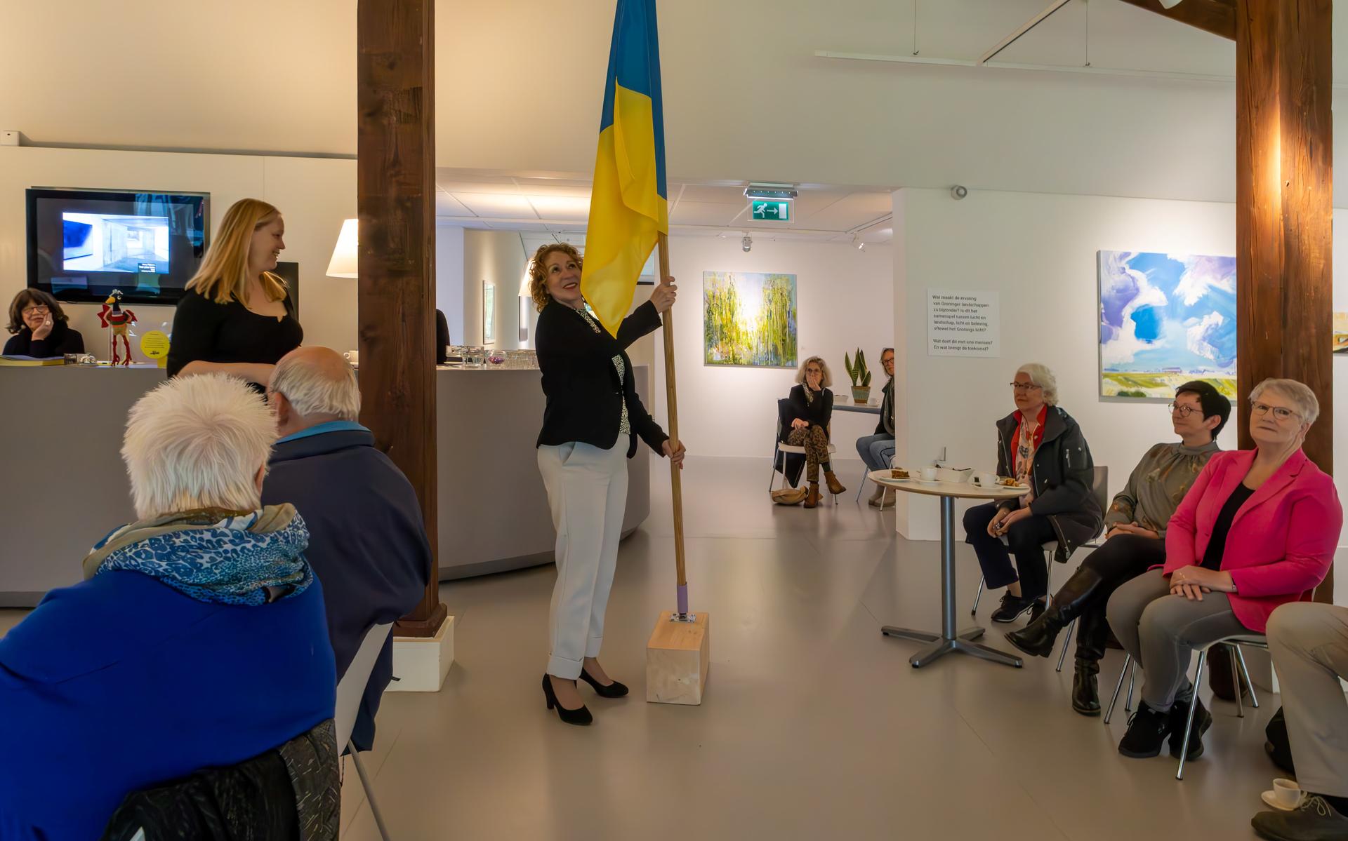 Wethouder Giny Luth plaatst de Gronings Vuur-vlag pontificaal in het MOW