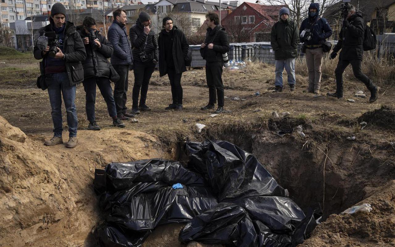 Journalisten en fotografen bij een massagraf in Boetsja, bij Kiev.