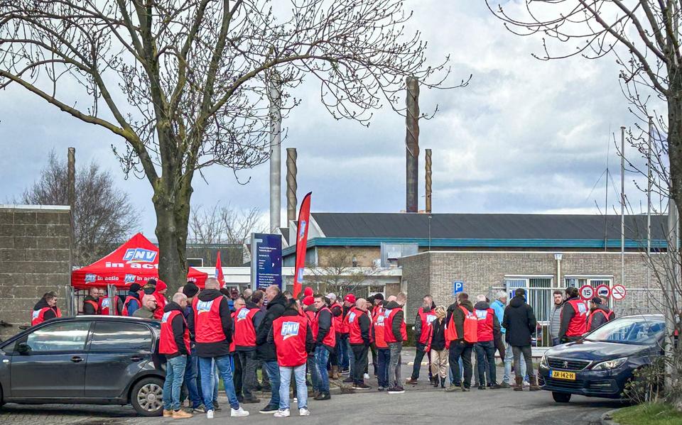 Stakende medewerkers bij Forbo Novilon tegen een achtergrond van schoorstenen waar geen rook uitkomt.