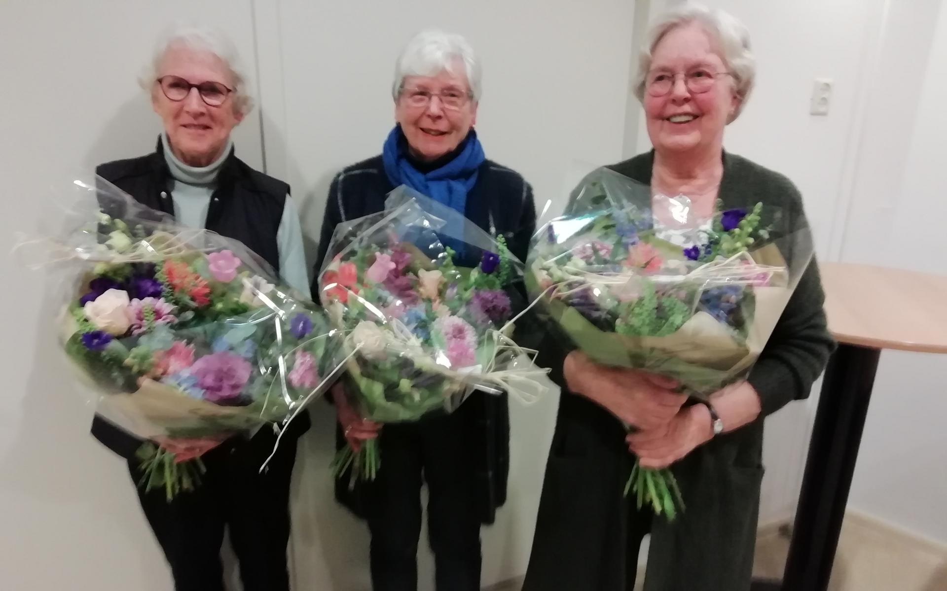 Drie jubilarissen met een grote bos bloemen. Ron van Lewe ontbrak wegens ziekte. Eigen foto