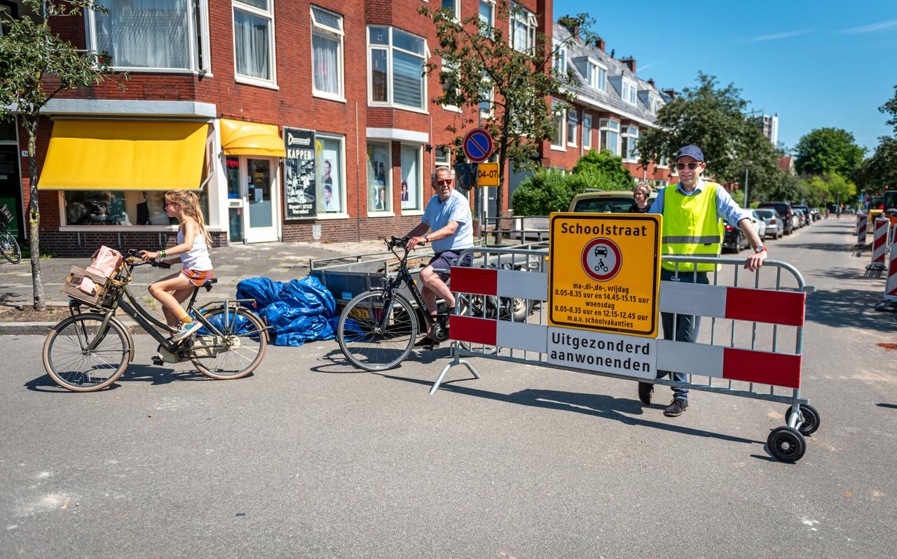 Afsluiting Schoolstraat. Verkeersregelaar Wouter Bierman (r) laat alleen fietsers en aanwonenden door. 