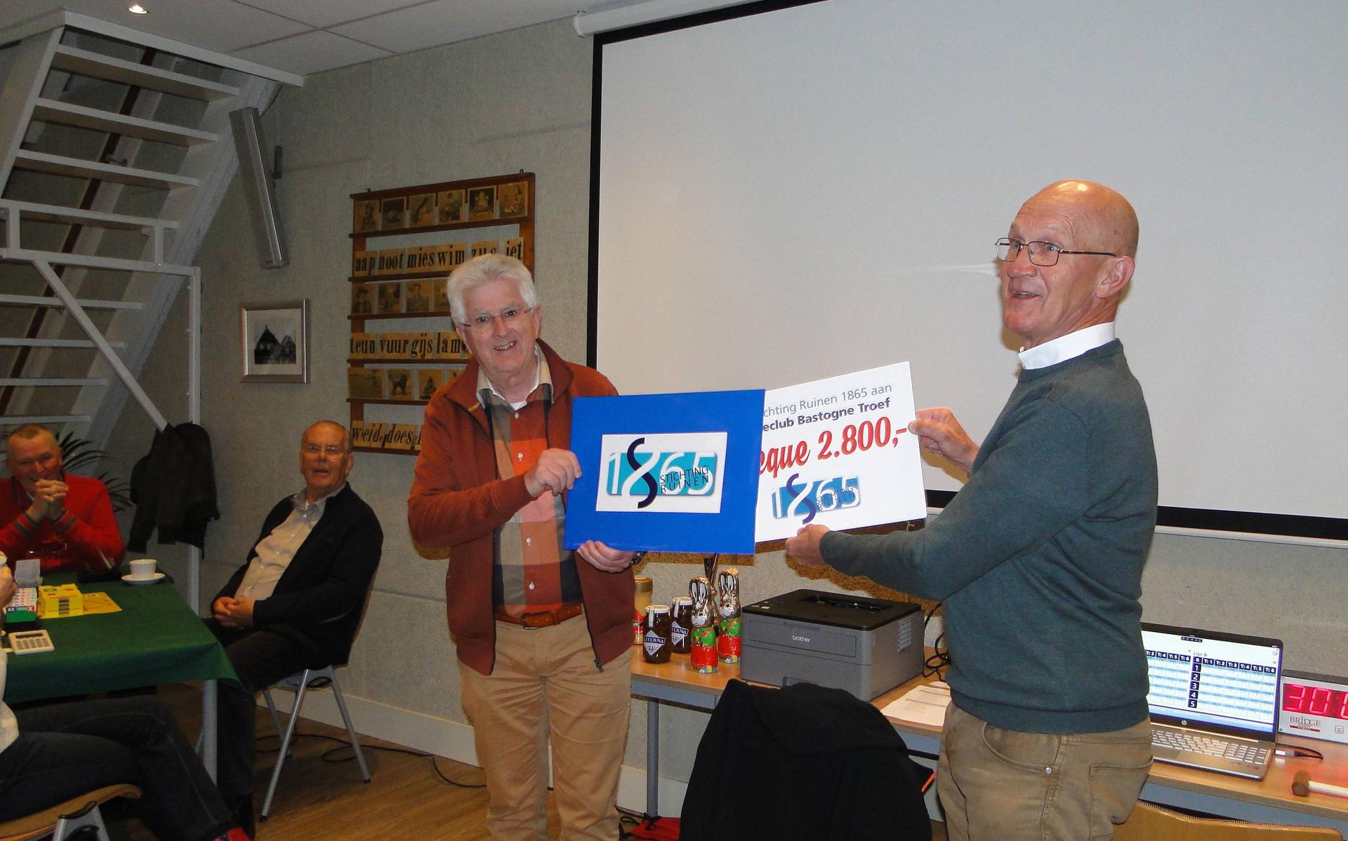 Johan van den Berg (links) overhandigt een cheque van 2.800 euro aan Arend Bijker, voorzitter van bridgeclub Bastognetroef. 
