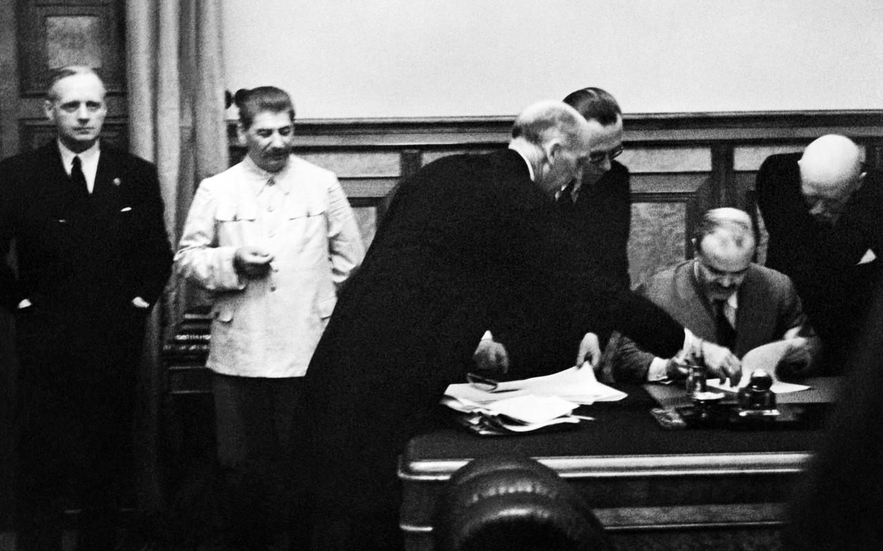 De Russische minister van Buitenlandse Zaken Molotov tekent op 23 augustus 1939 in het Kremlin in Moskou het verdrag. De Duitse minister van Buitenlandse Zaken Von Ribbentrop staat geheel links. Naast hem de Russische dicator Stalin.