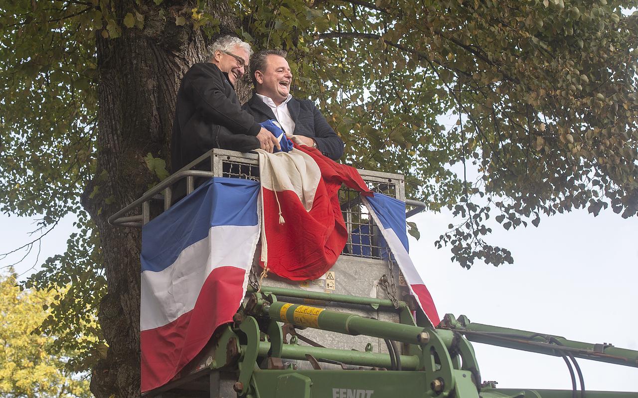 Burgemeester Renze Bergsma (rechts) en boer Jan Boesjes halen een vlag uit een boom.
