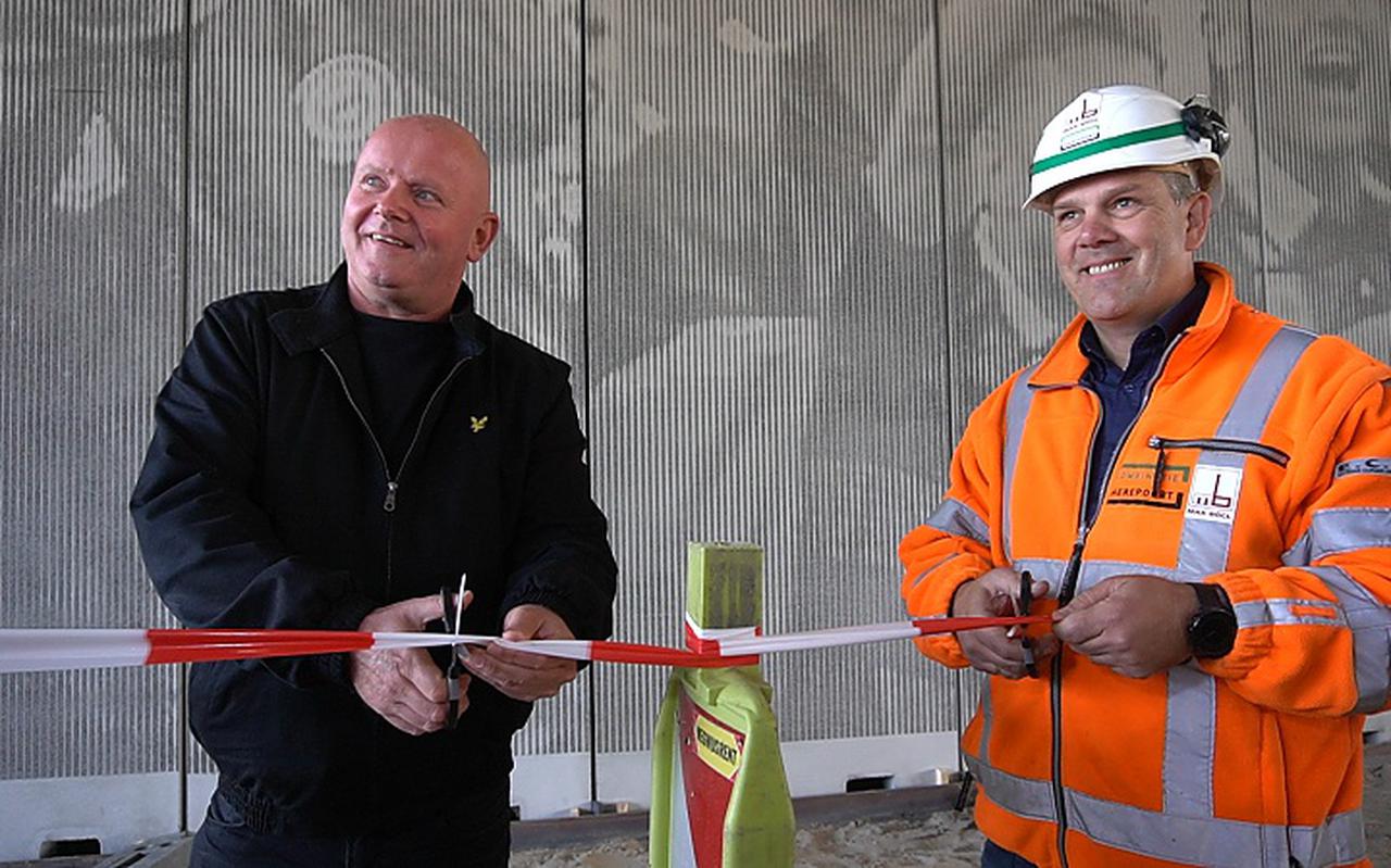 John de Jonge (links) van de supportersvereniging van FC Groningen onthult het kunstwerk op het viaduct.