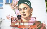 Kunstenaar Jack Lack is bezig met de grote muurschildering van het portret van Frida Kahlo aan de Beilerstraat.