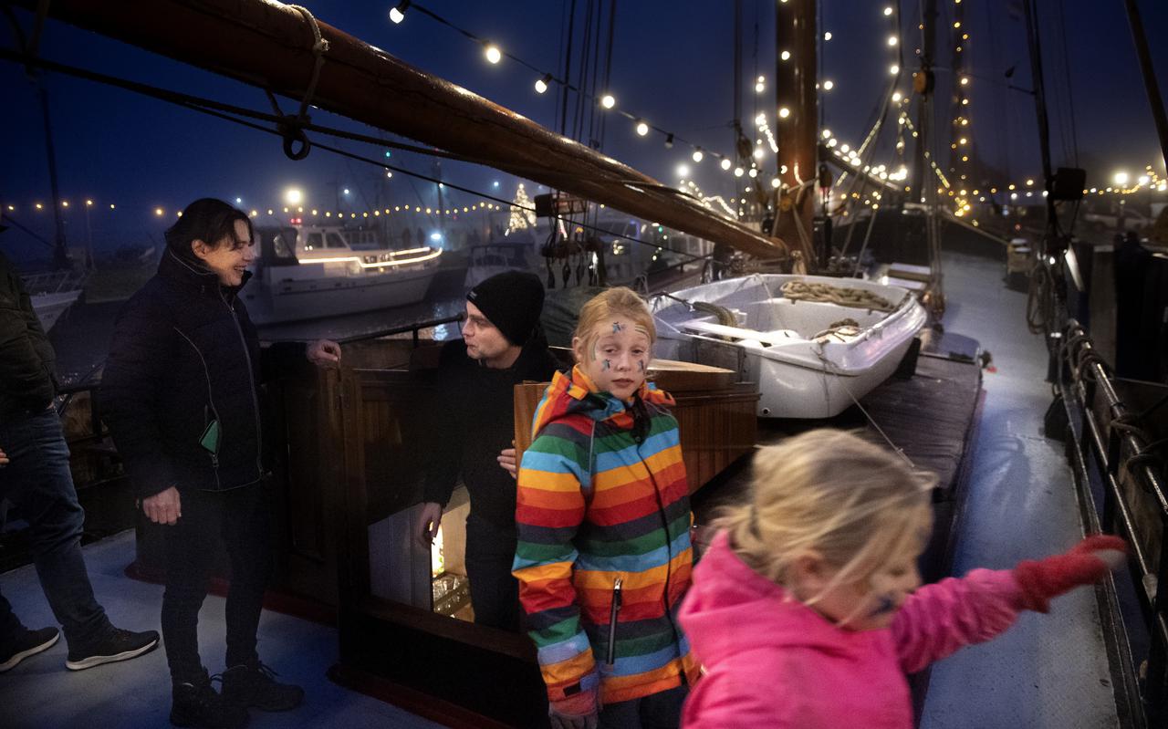 Bezoekers aan boord van een met lichtjes versierde boot.