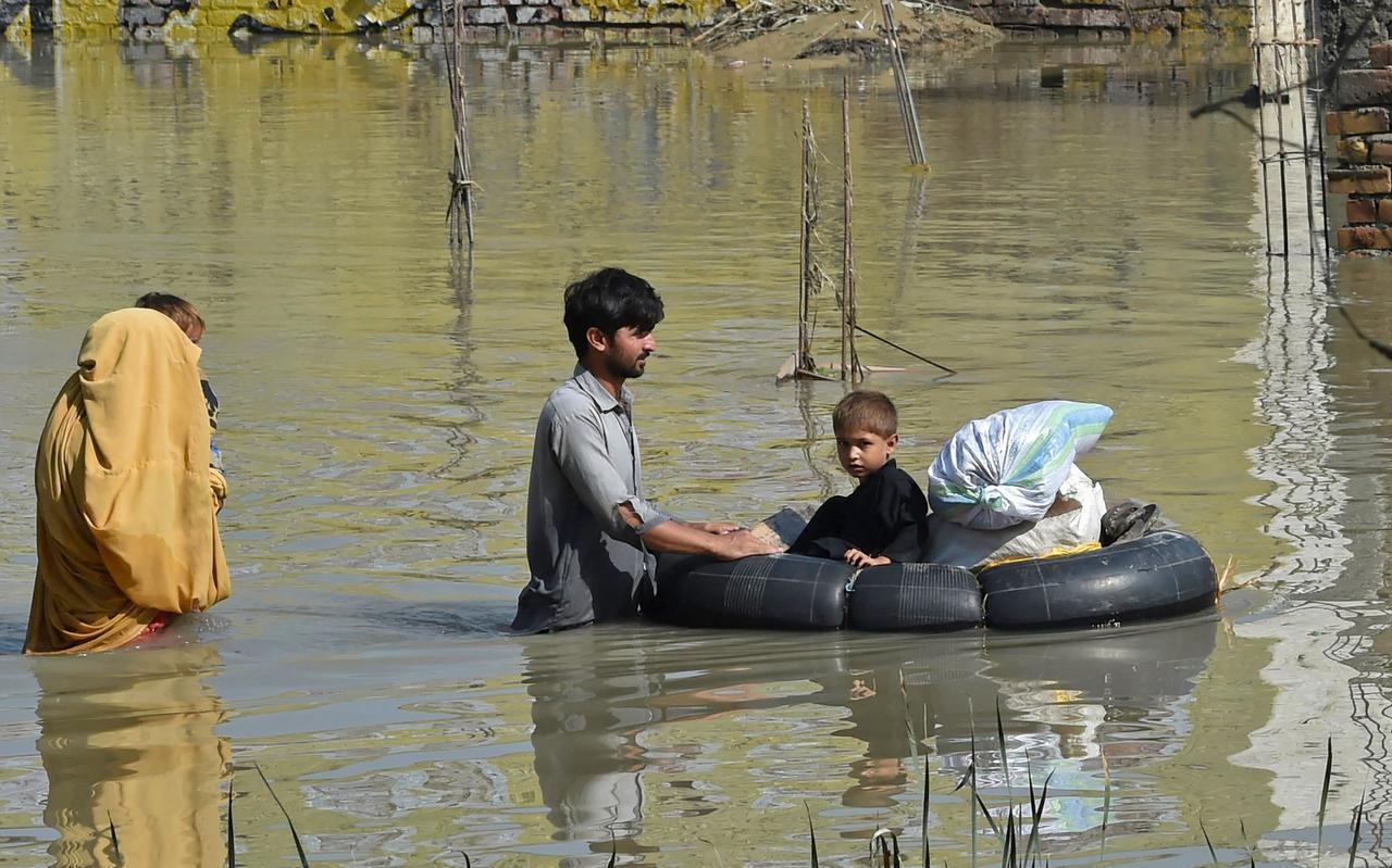 Een gezin waadt deze zomer door een overstromingsgebied na zware moessonregens in Pakistan. 