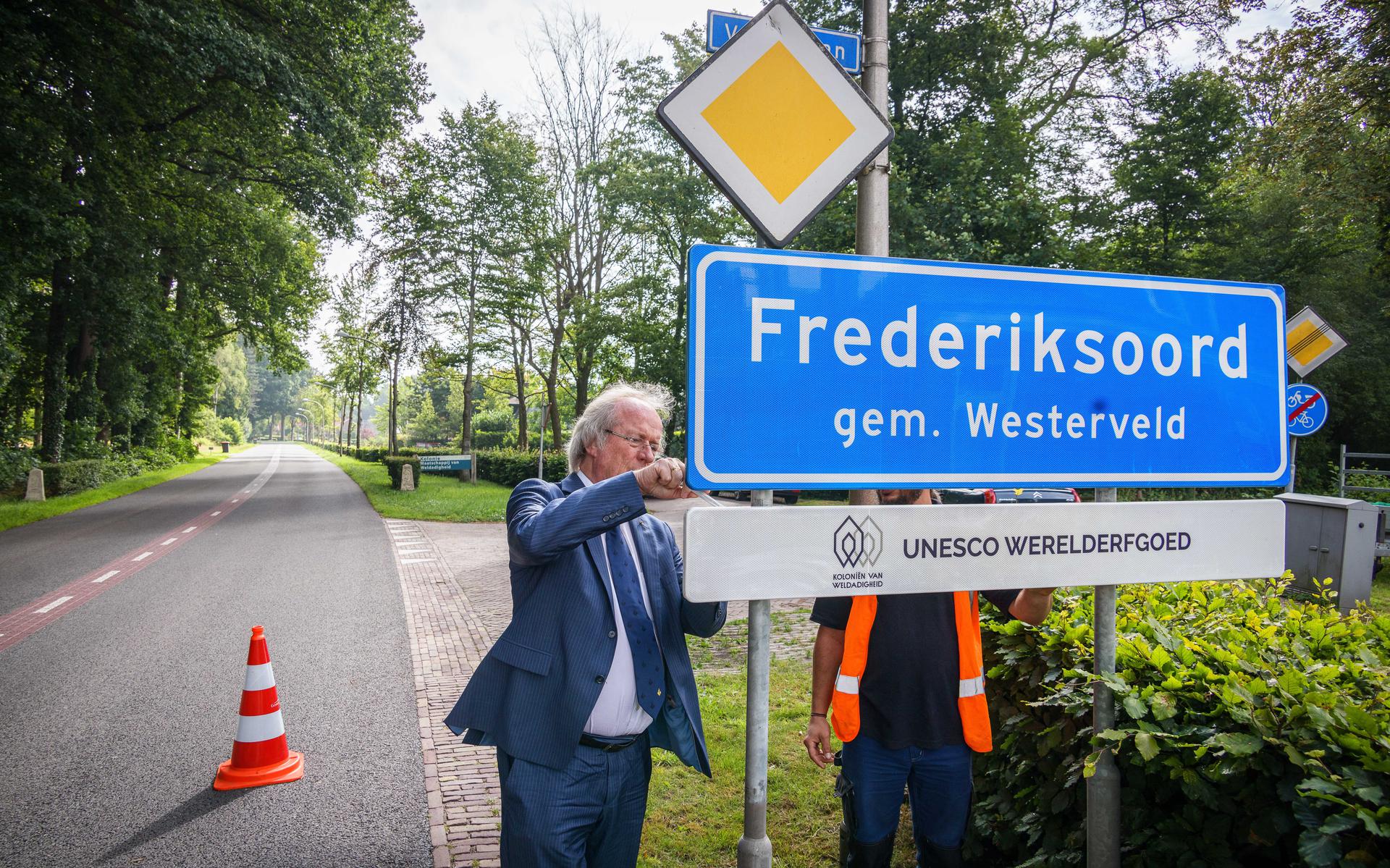 Burgemeester Rikus Jager hangt het bordje over Unesco onder het plaatsnaambord.