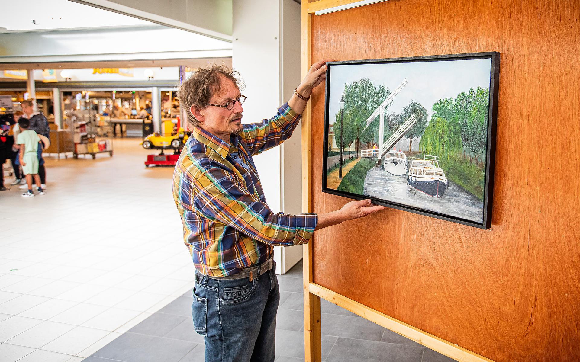 Arnoud van Sante hangt het schilderij 'Toen was een brug nog heel gewoon' op. Het is onderdeel van een expositie van Pekelder kunstenaars met bruggen als thema. 