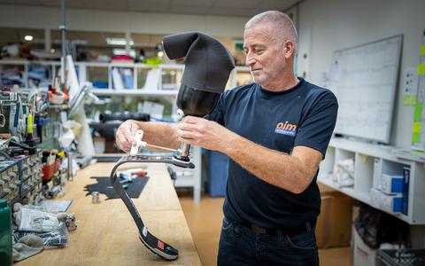 Henk Zijlstra sleutelt in de werkplaats van OIM in Haren aan een prothese.