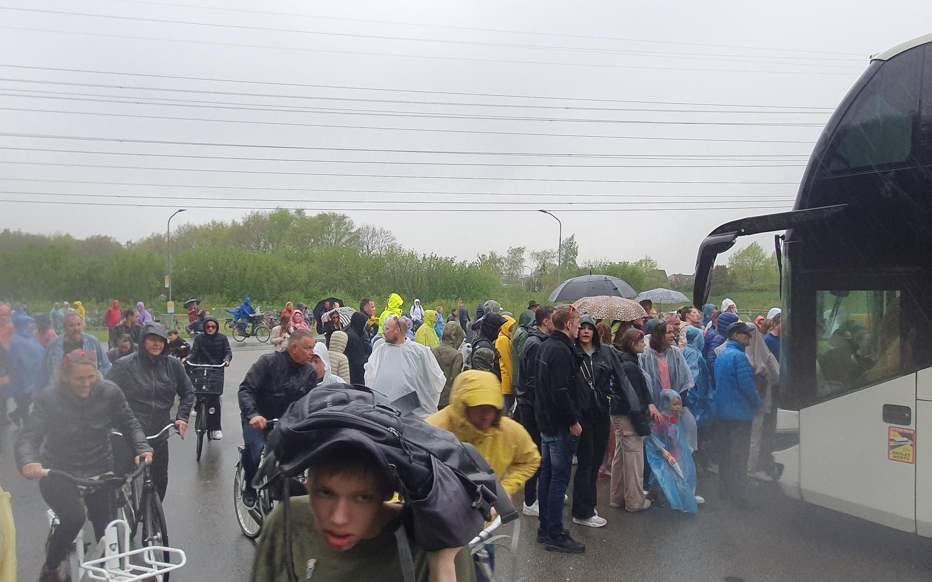 Bezoekers van het Bevrijdingsfestival in Assen zoeken beschutting tegen de regen.
