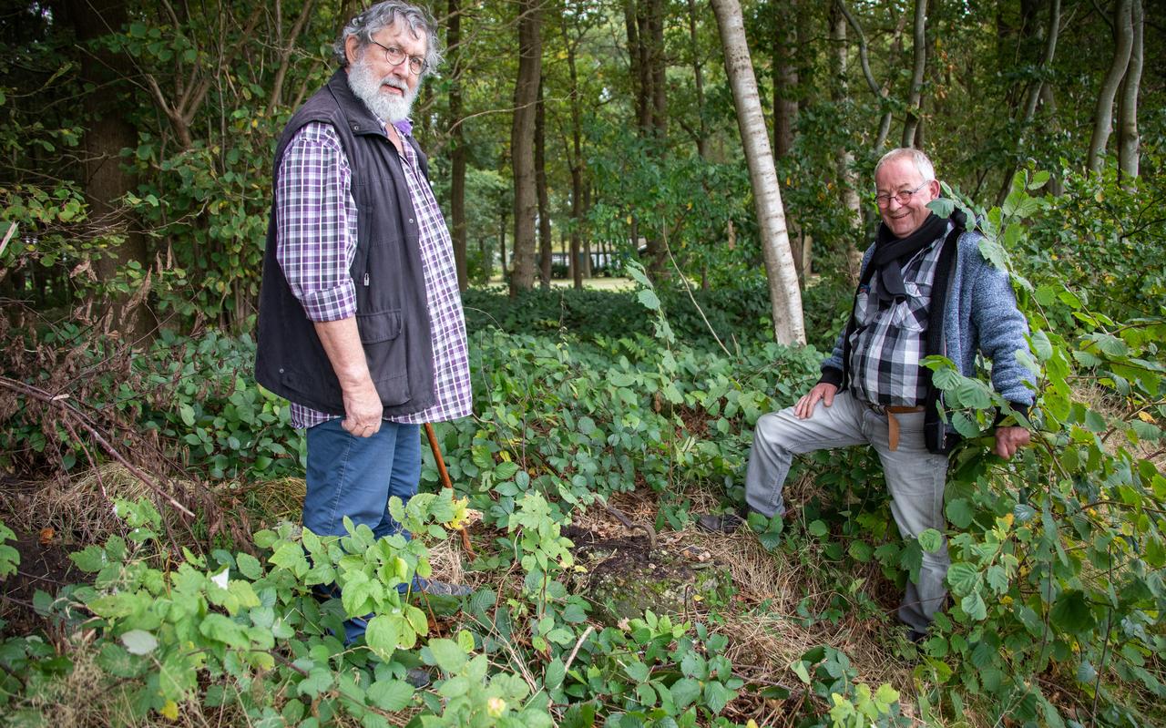 Vrijwilligers Geert Oost (links) en Gerard Weinans bij de fundering van de wachttoren, nabij de tussen de bomen door zichtbare barak. Vrijwilligers Geert Oost (links) en Gerard Weinans bij de fundering van de wachttoren, nabij de tussen de bomen door zichtbare barak.