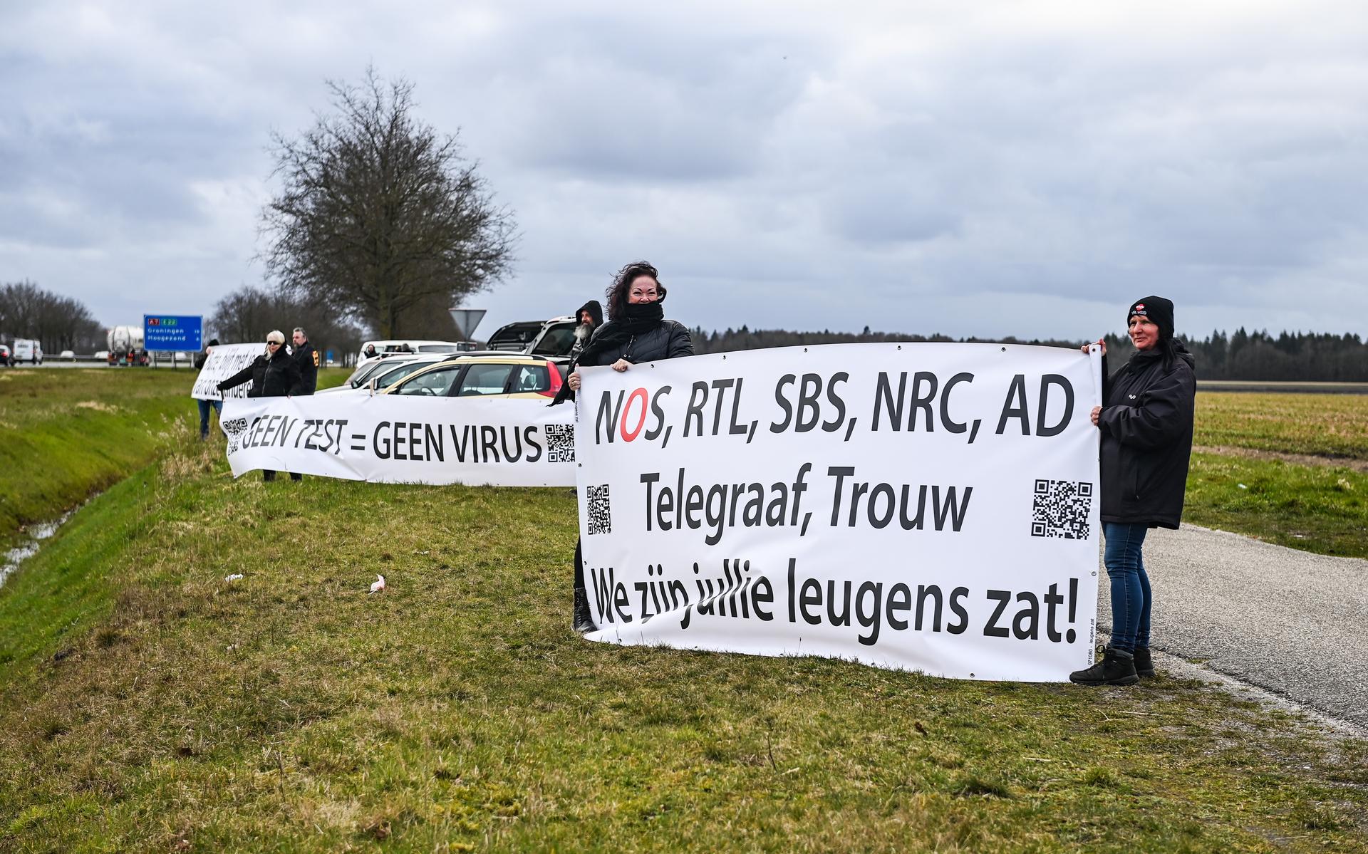 Actievoerders staan met spandoeken tegen coronabeleid en 'leugens van media' langs A7 bij Zuidbroek 