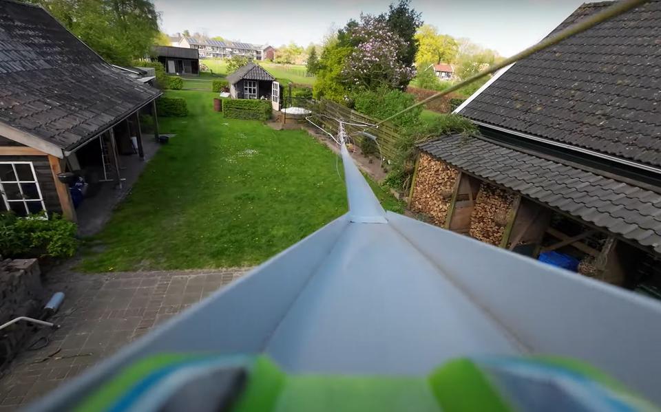 Een 'still' uit de video, waarin het autootje door het dakraam de tuin in rijdt.