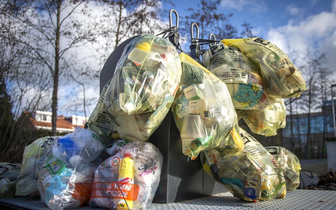 Stockfoto van plasticafval in afvalzakken dat ligt te wachten totdat het door een vuilniswagen wordt opgehaald.
