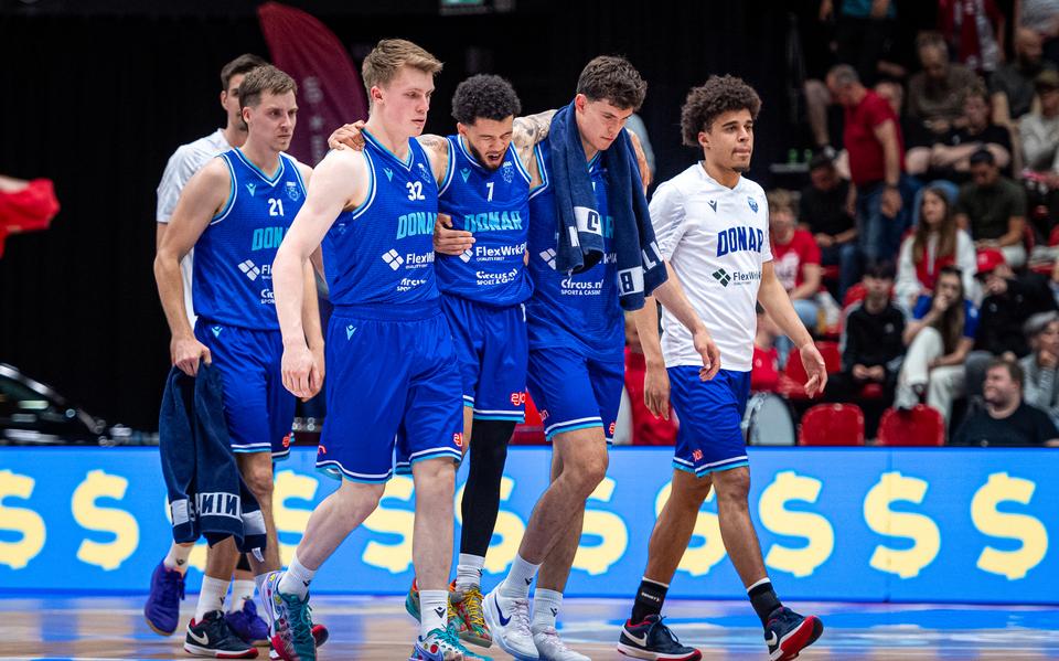 Ondersteund door Kjeld Zuidema (links) en Sam van Oostrum verlaat de geblesseerd geraakte sterspeler van Donar Tavian Dunn-Martin het veld in de Maaspoort.
