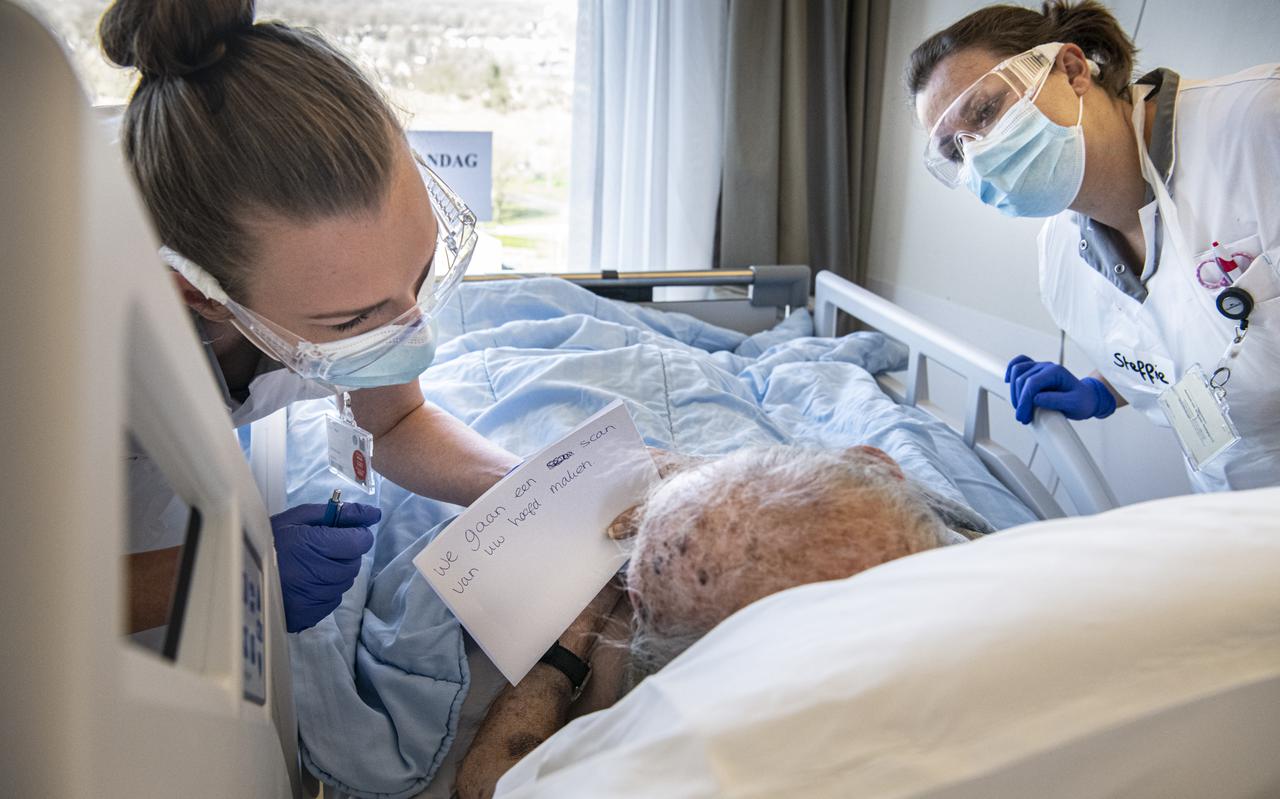 Twee verpleegkundigen aan het bed bij een coronapatiënt. 