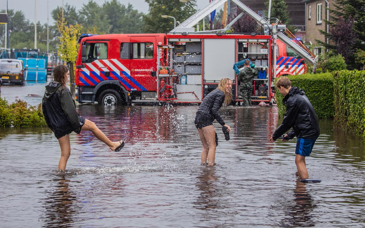 Door de hevige regenval zijn er op veel plekken in Friesland, zoals hier in Woudsend, straten overstroomd. De oefening met zandzakken moet dit in de toekomst voorkomen.