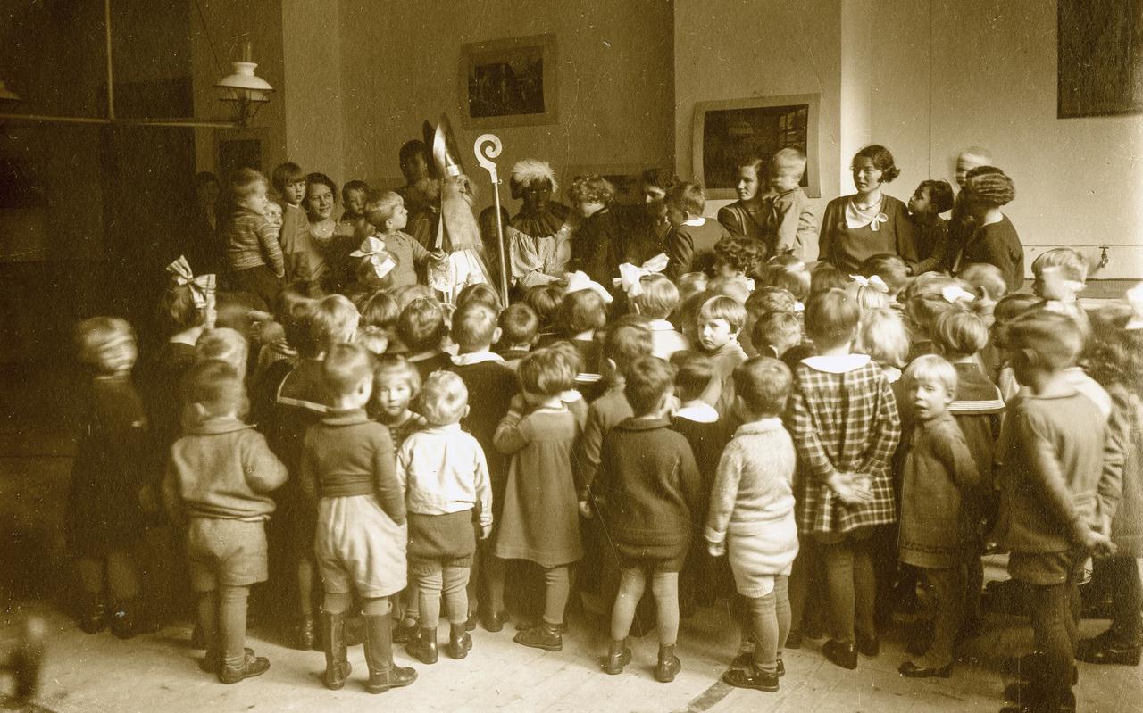 Bezoek van de moderne Sinterklaas met zijn hulpknecht aan een lagere school in Groningen, in de jaren twintig. 