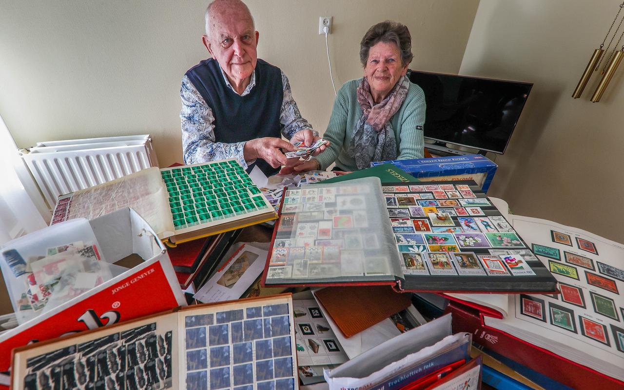 Hans en Thea van der Meulen buigen zich over de postzegelverzameling die Wolter van der Heide hen heeft geschonken. 