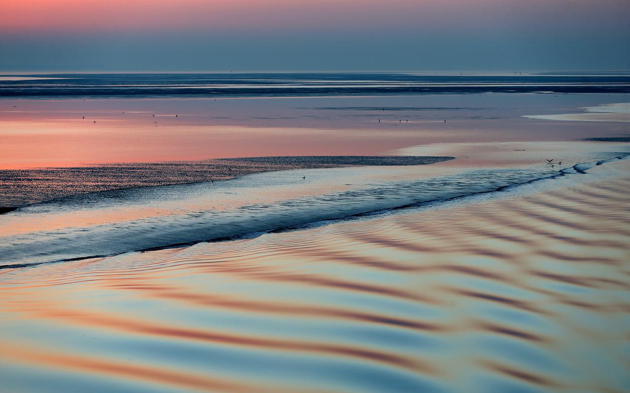 Zonsondergang aan de horizon van de Waddenzee. 
