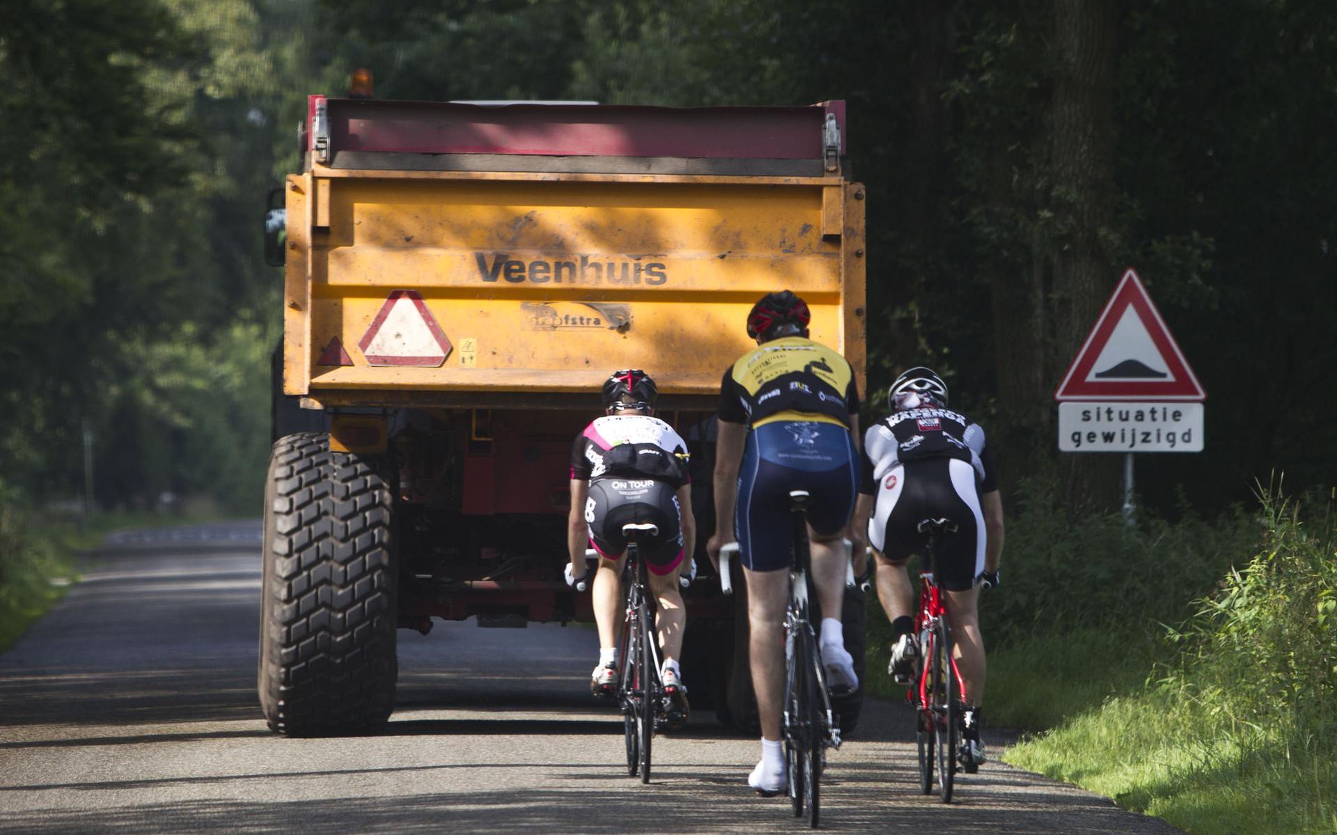 Fietsers achter een trekker.