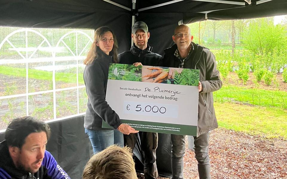 Voorzitter Hans Christiaanse (rechts) overhandigt het bordje en bijbehorende cheque aan Jan-Jaap en Marjolein Bakker van de Sociale Voedseltuin De Pluimerije. 